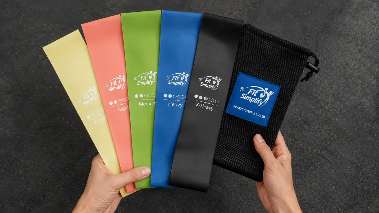 Close-up of a hand holding Fit Simplify resistance bands fanned out showing all five resistance levels